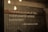 A quote is displayed on a textured concrete wall, illuminated by hanging Edison bulb lights. The text emphasizes the importance of kindness and is attributed to Muhammad SAW.