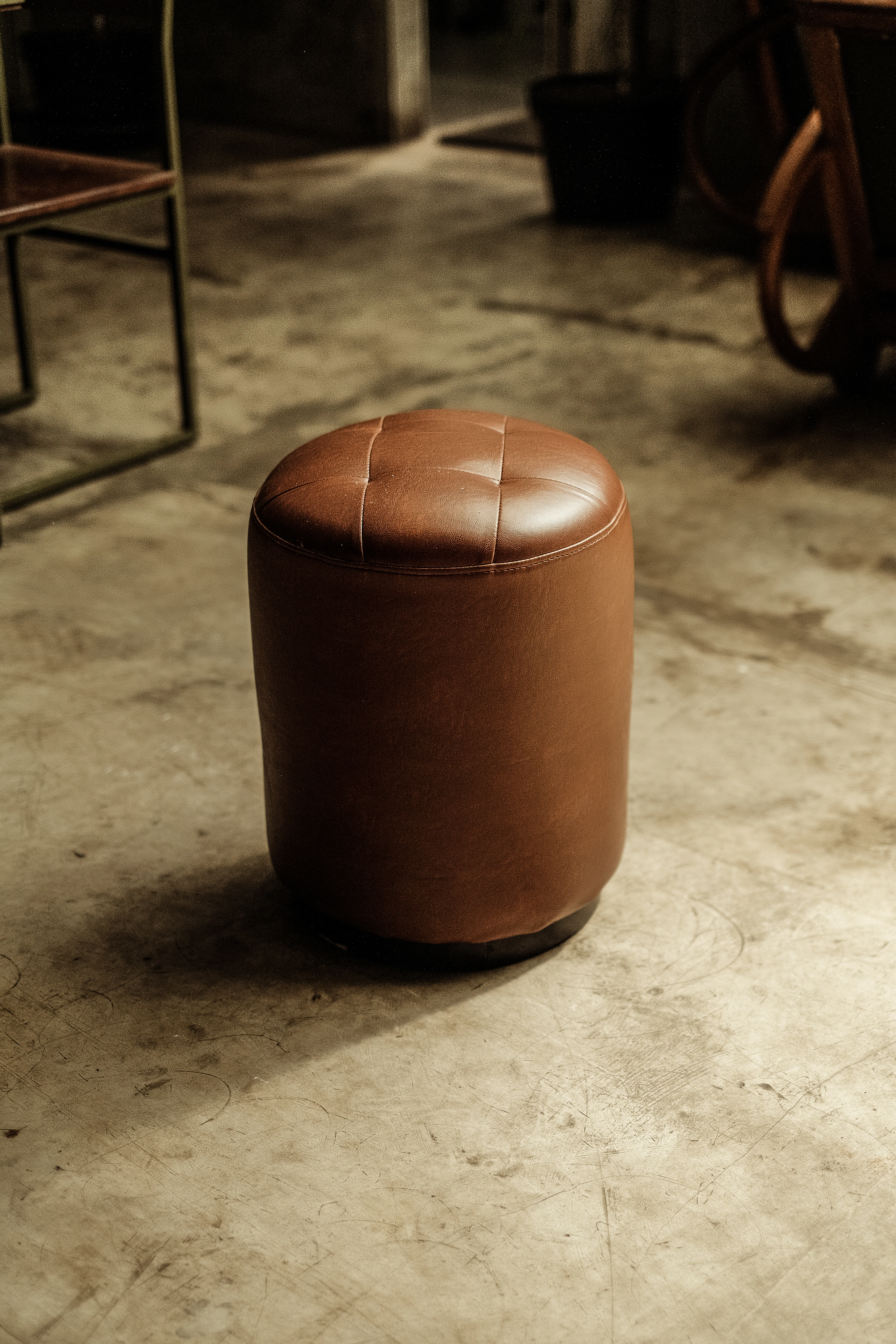 Cognac leather pouf on a concrete floor