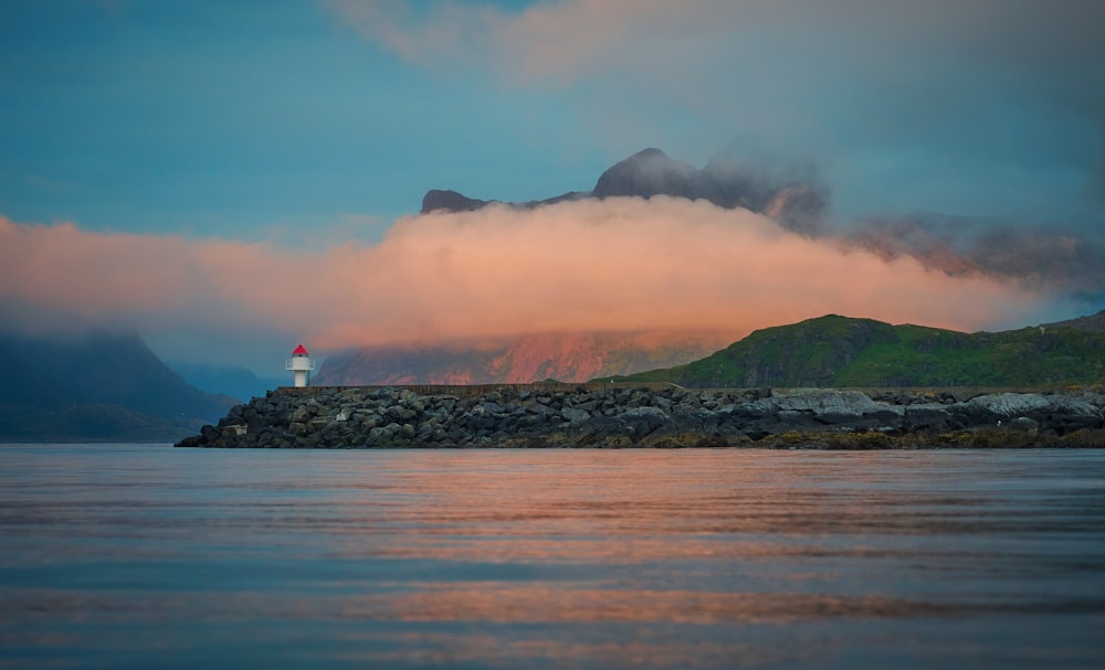 a lighthouse on a rock outcropping in the middle of a body of