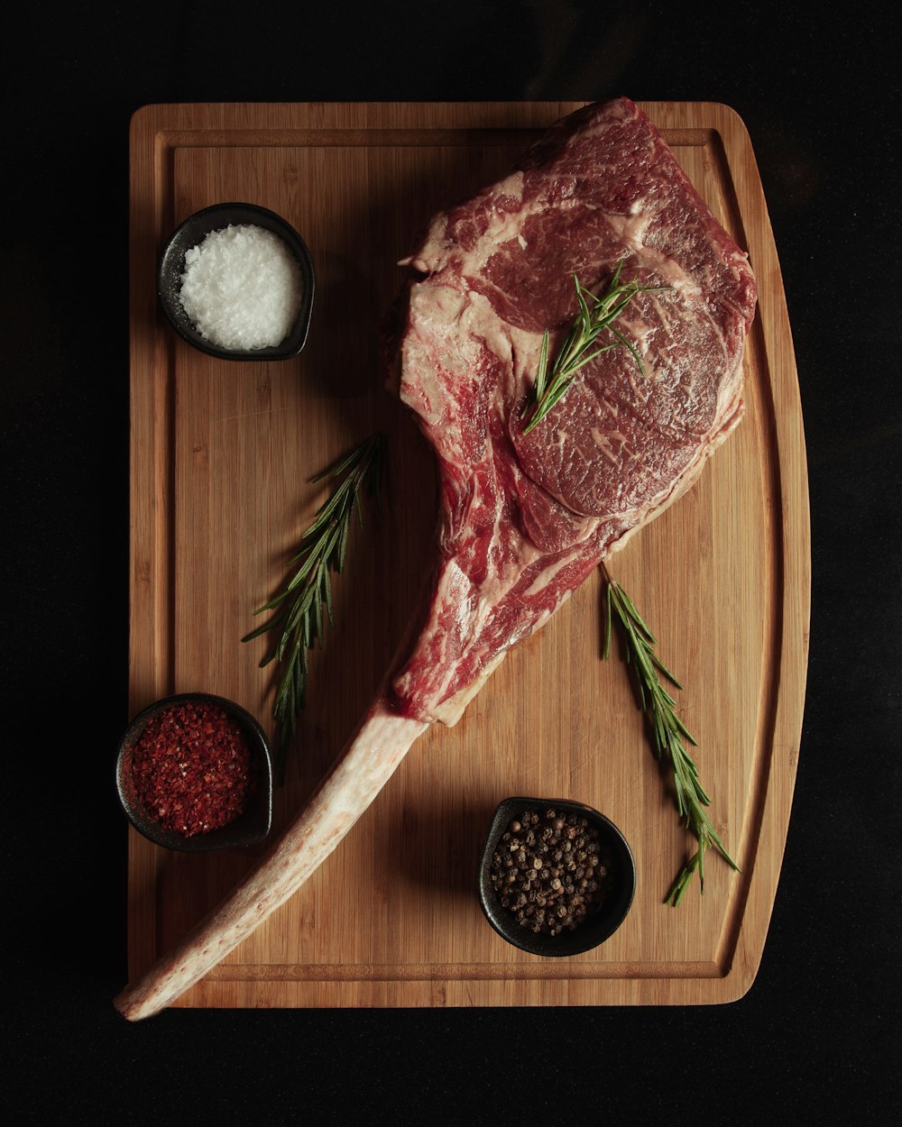 a piece of steak on a cutting board with spices and seasonings