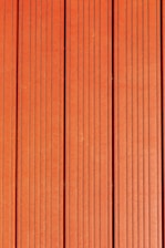 Four vertically aligned wooden planks with a rich brown color. Each plank has evenly spaced grooves running lengthwise, providing a textured appearance. Subtle variations in shade and grain are visible across the surface.