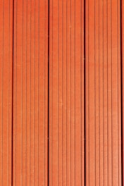 Four vertically aligned wooden planks with a rich brown color. Each plank has evenly spaced grooves running lengthwise, providing a textured appearance. Subtle variations in shade and grain are visible across the surface.