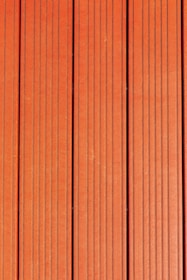 Four vertically aligned wooden planks with a rich brown color. Each plank has evenly spaced grooves running lengthwise, providing a textured appearance. Subtle variations in shade and grain are visible across the surface.
