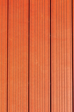 Four vertically aligned wooden planks with a rich brown color. Each plank has evenly spaced grooves running lengthwise, providing a textured appearance. Subtle variations in shade and grain are visible across the surface.