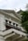 A historic building with classical architecture featuring ornate decorative elements, white facade, and a balcony. The words 'Bank Indonesia' are prominently displayed on the building. A tree with lush green leaves partially obscures the building.