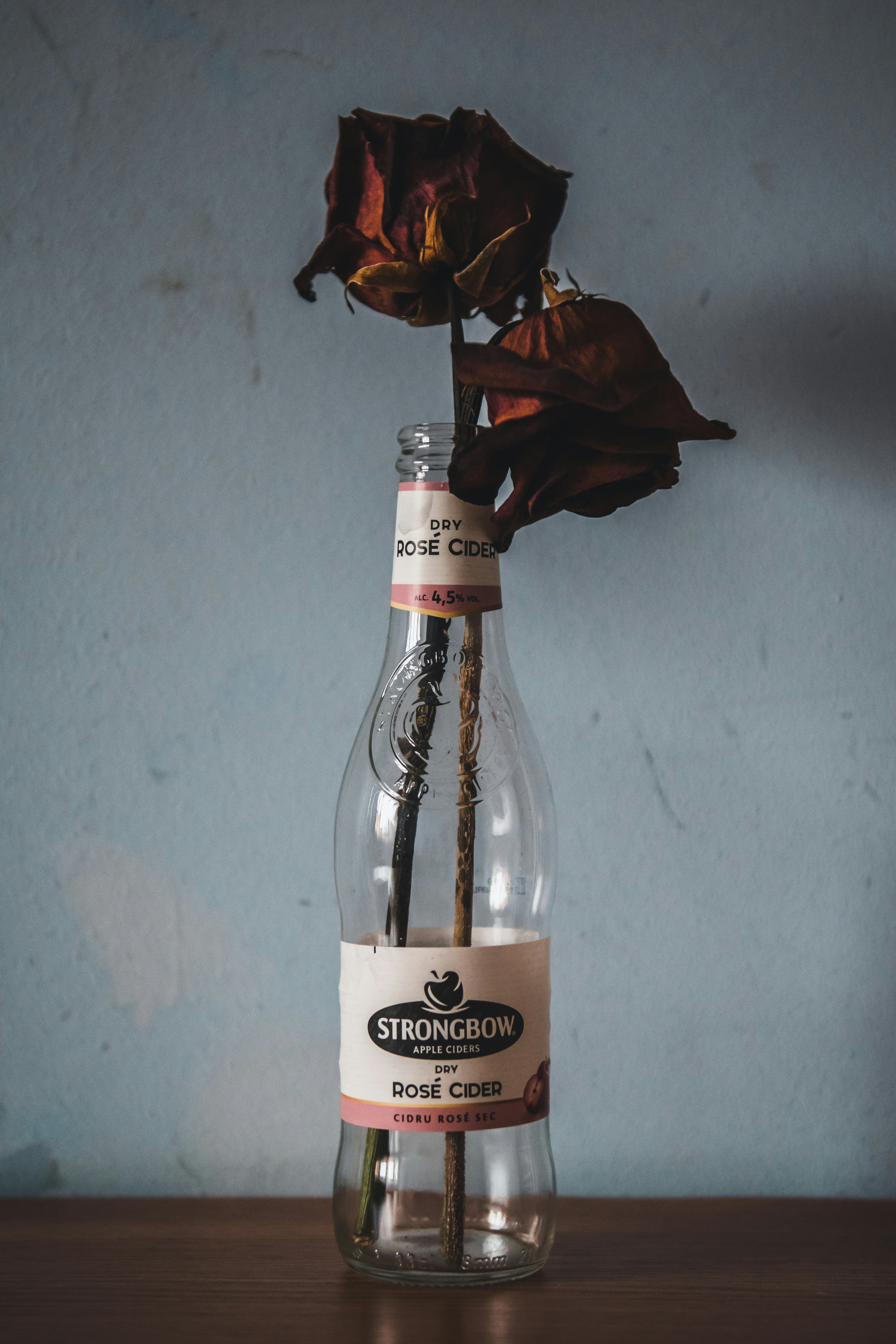 빨대가 튀어 나온 유리 병에 장미 한 송이;