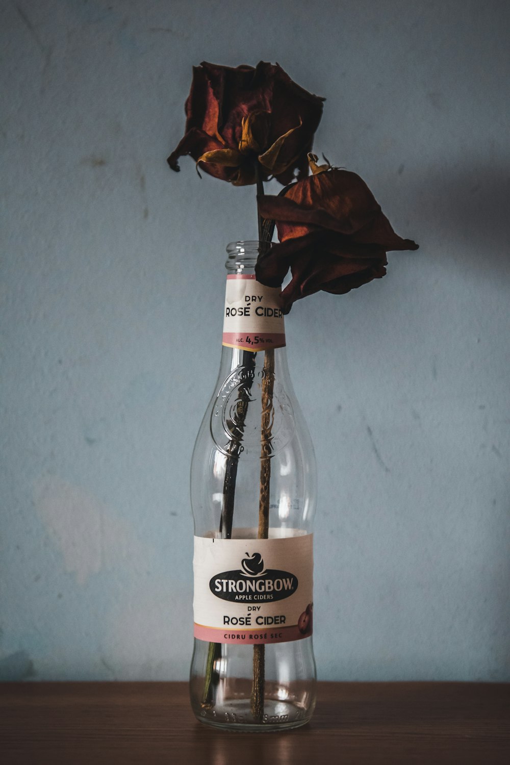 a single rose in a glass bottle with a straw sticking out of it