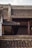 An intricately designed traditional Asian roof features layered, curved tiles with ornate carvings and decorative elements. The structure showcases wooden beams and decorative latticework windows, highlighting a blend of craftsmanship and architectural beauty. The lighting casts soft shadows, enhancing the texture of the roofing tiles.