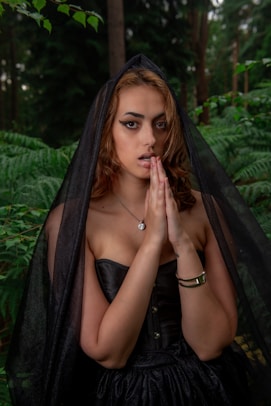 a woman in a black dress with a veil on her head