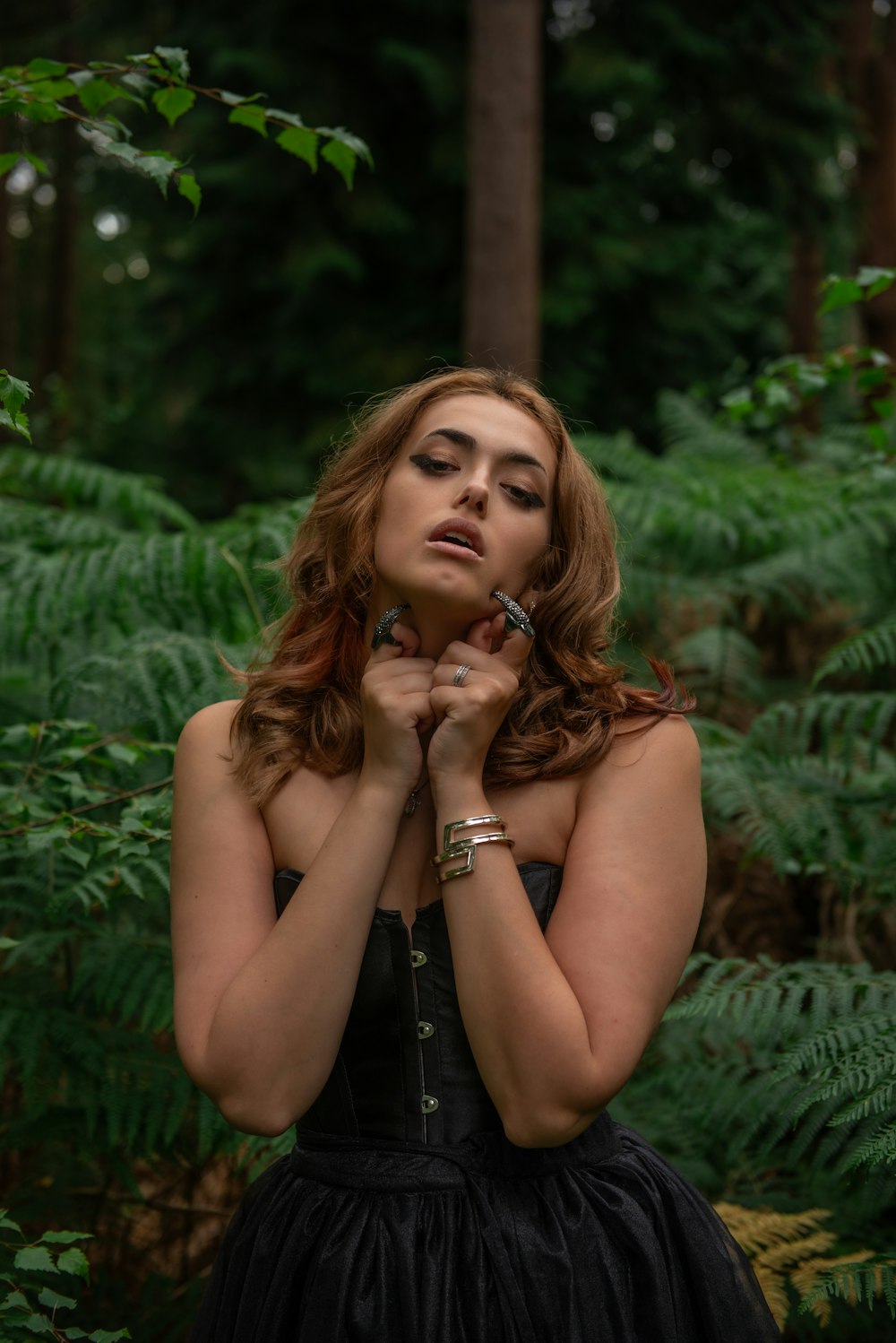 a woman in a black dress standing in a forest