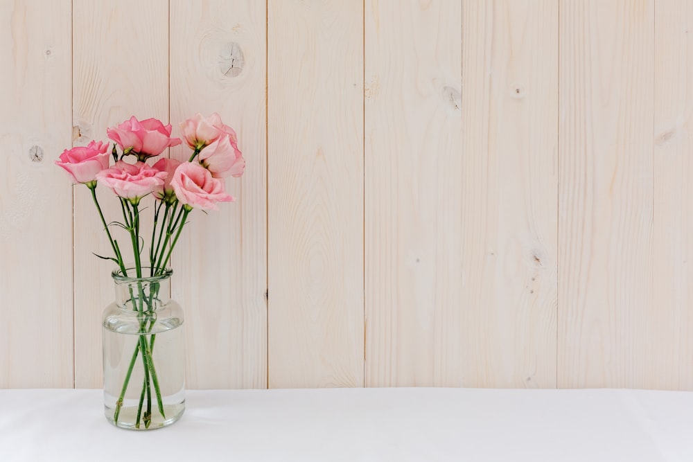 a vase of pink roses on a white table