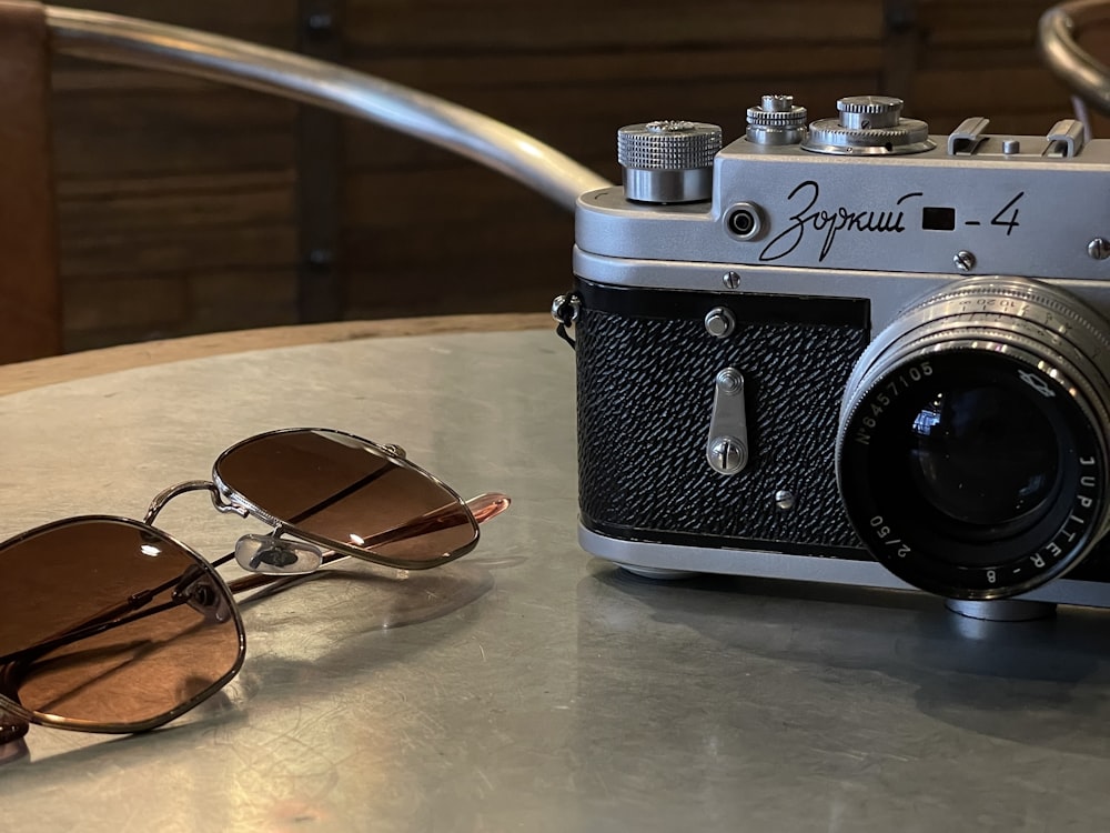 a pair of sunglasses sitting on top of a table next to a camera