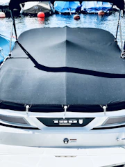 Close-up of a sleek boat covered with a perfectly fitted navy blue canvas cover on a sunny day.