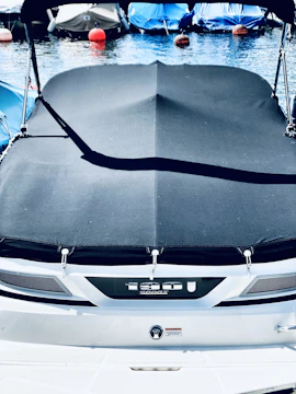 Close-up of a sleek boat covered with a perfectly fitted navy blue canvas cover on a sunny day.