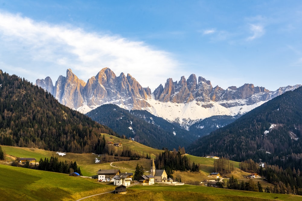 the mountains are covered in snow and green grass