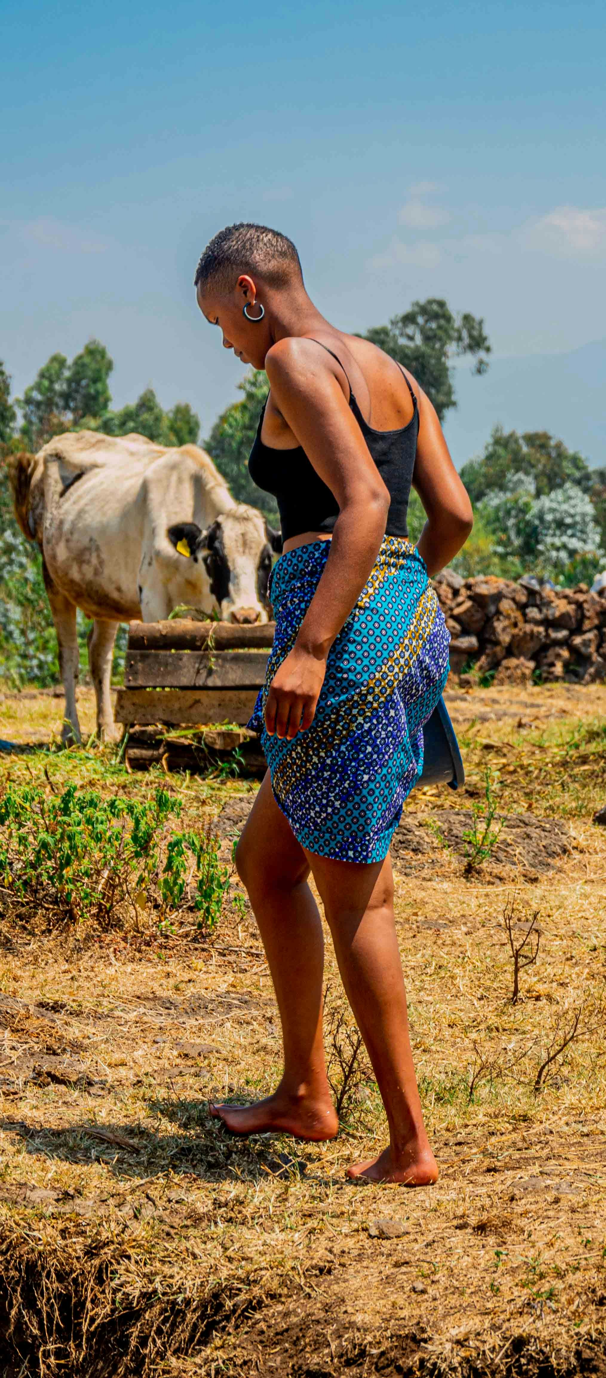 a woman walking in a field with a cow in the background