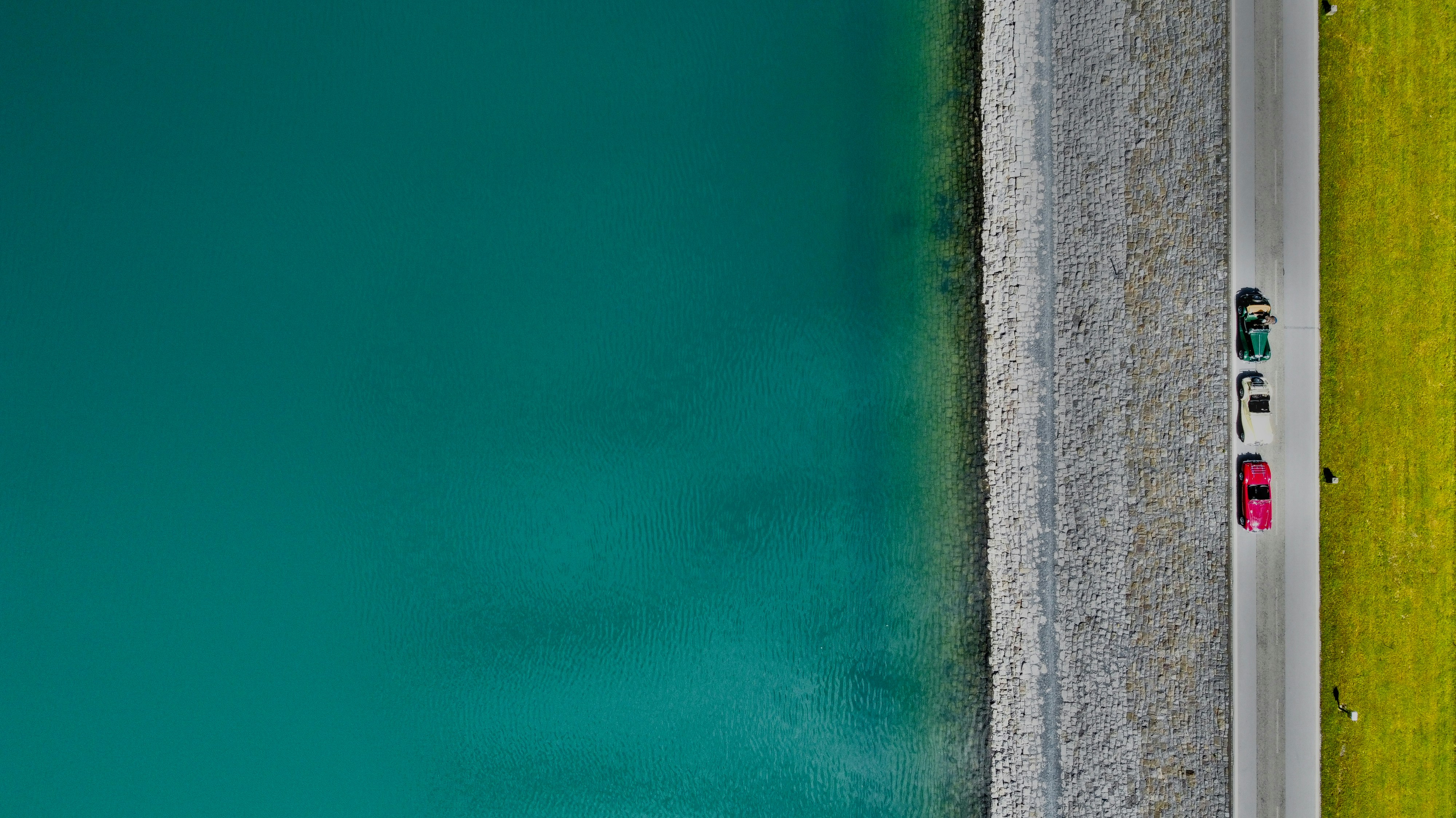 a car driving down a road next to a body of water