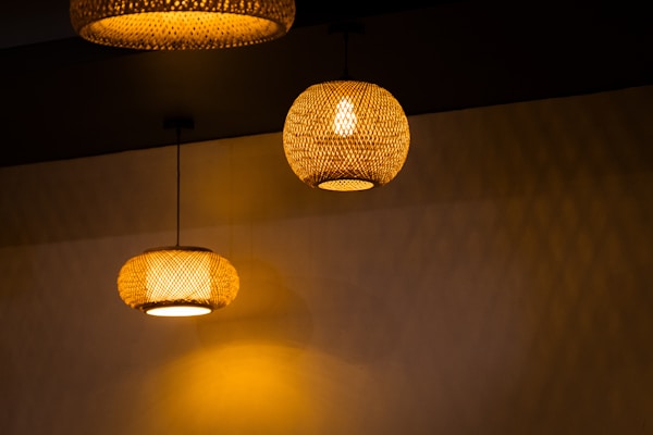 Elegant wall lights with woven rattan shades illuminating a softly lit hallway.