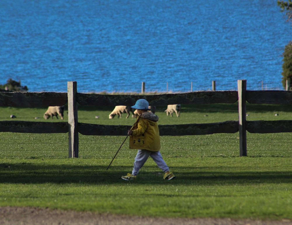 a little boy walking across a lush green field