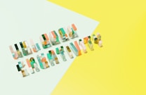 Colorful and transparent 3D letters spelling out 'Unknown Creativity' lay on a minimalistic, pastel-colored background that is divided into light green and yellow sections.