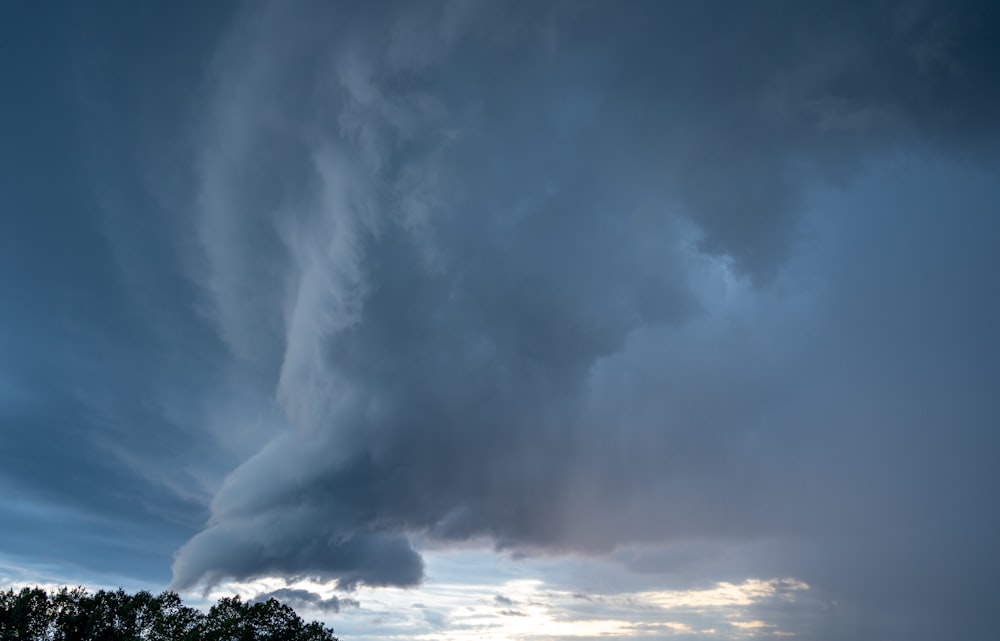 Un très gros nuage dans le ciel au-dessus d’un champ