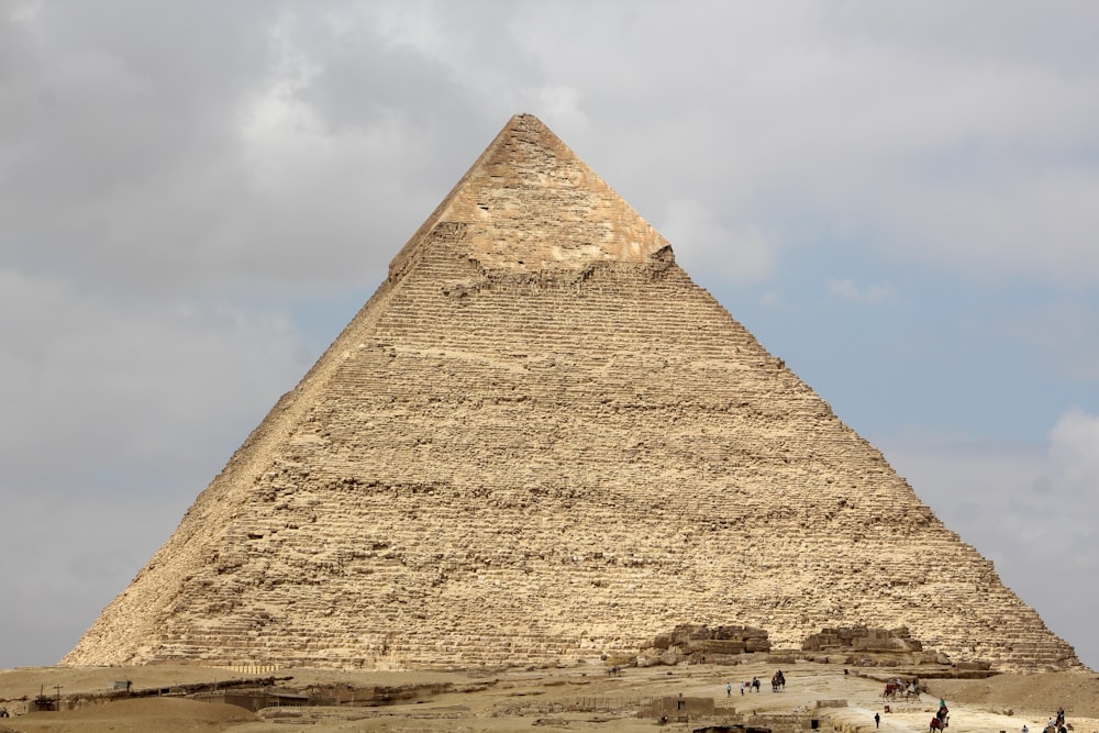 a group of people standing in front of a large pyramid