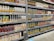 Shelves stocked with various brands and flavors of packaged fruit juices. The cartons are neatly arranged and display a variety of fruit illustrations, indicating different juice flavors. The shelves are labeled with price tags, and the atmosphere resembles a well-organized grocery store aisle.