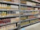 Shelves stocked with various brands and flavors of packaged fruit juices. The cartons are neatly arranged and display a variety of fruit illustrations, indicating different juice flavors. The shelves are labeled with price tags, and the atmosphere resembles a well-organized grocery store aisle.