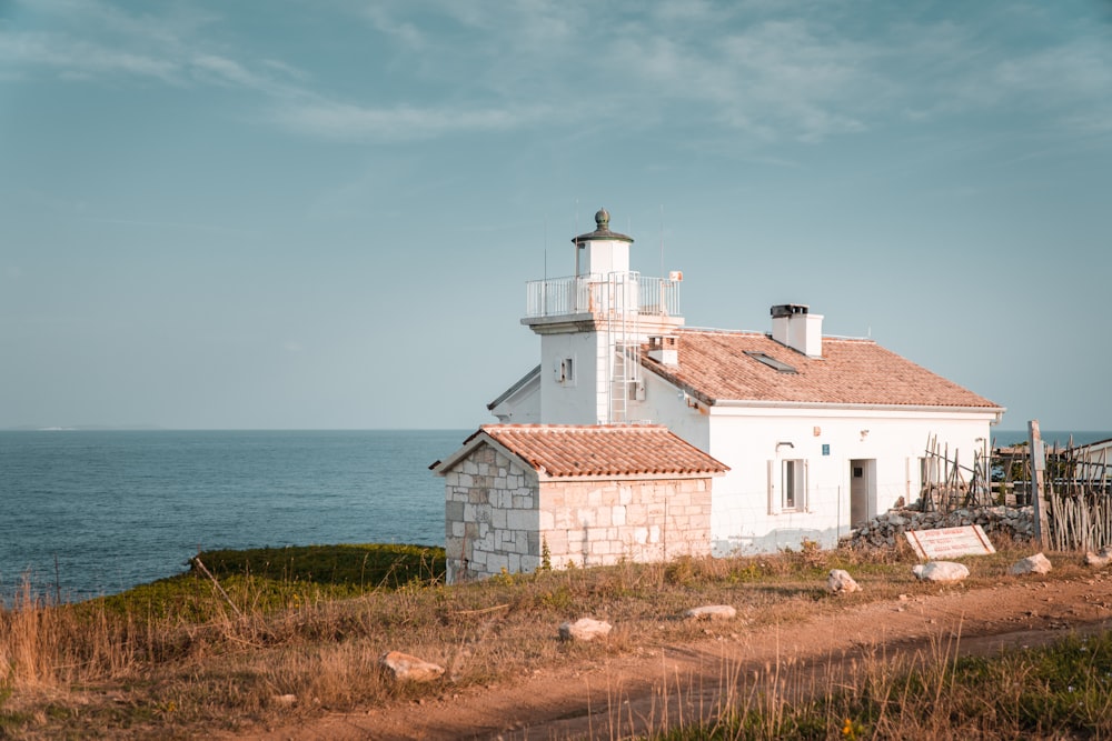 a white house sitting on top of a hill next to the ocean