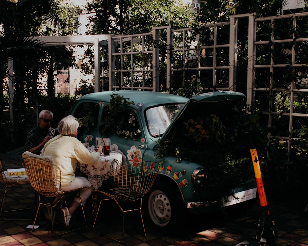 a couple of people sitting at a table in front of a car