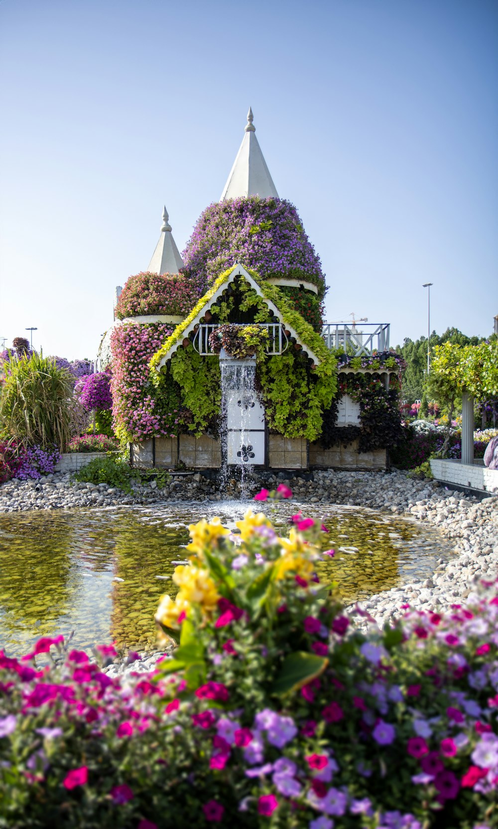 a house covered in flowers next to a body of water