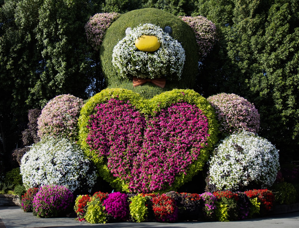 a teddy bear made out of flowers in the shape of a heart