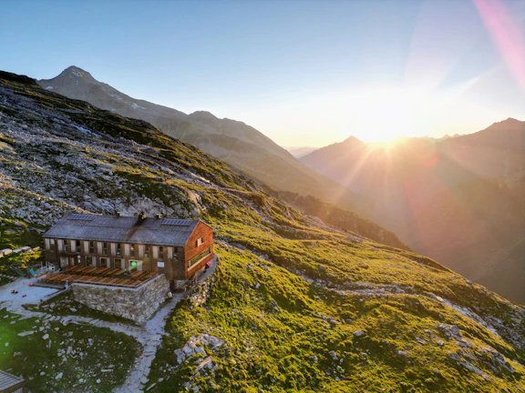 Sunset over the rustic cabins with mountains in the background, casting warm golden light.