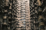 A densely packed residential building with numerous windows and balconies, creating a maze-like architectural pattern. The repetitive structure and close proximity of the apartment units suggest an urban environment with limited space.
