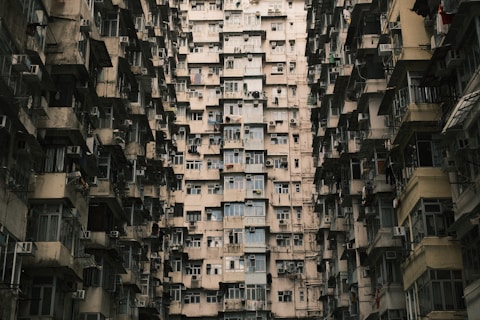 A densely packed residential building with numerous windows and balconies, creating a maze-like architectural pattern. The repetitive structure and close proximity of the apartment units suggest an urban environment with limited space.