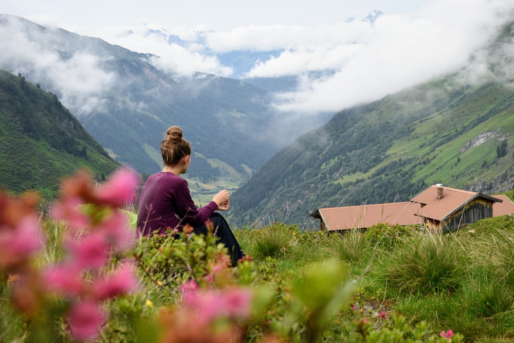 a woman sitting on top of a lush green hillside