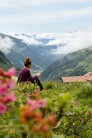 a woman sitting on top of a lush green hillside