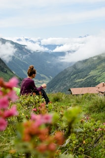 a woman sitting on top of a lush green hillside