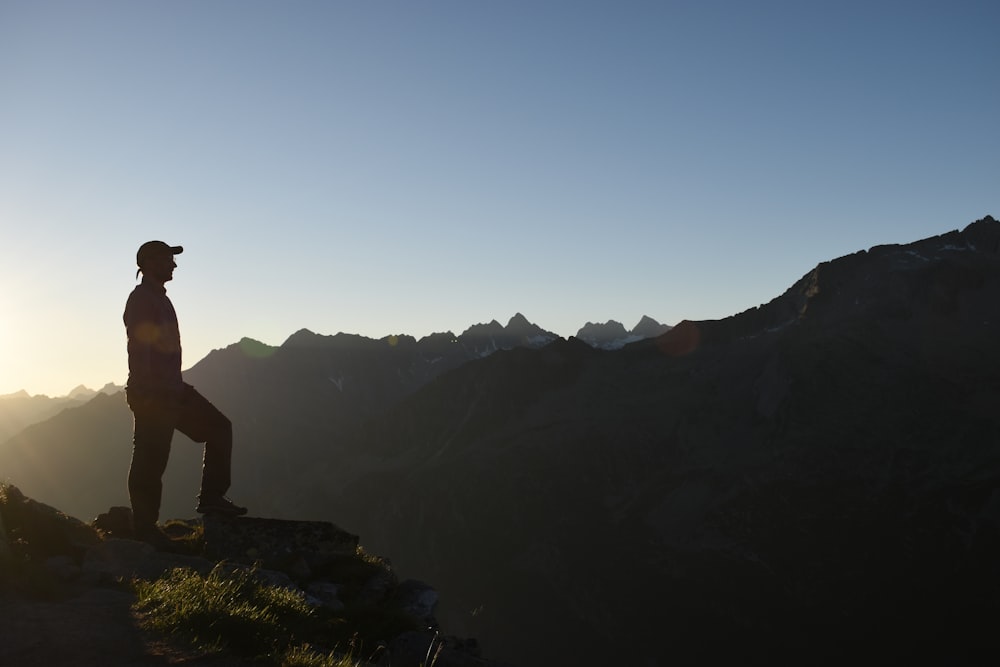 a man standing on top of a mountain at sunset