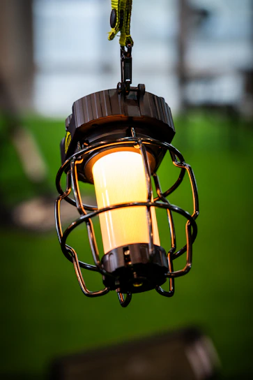 A warm-lit cage style pendant lamp hanging over a rustic wooden table.