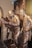 Bronze statues of three men in traditional attire, engrossed in examining a large map or document. The scene is set against a relief background depicting an urban environment with buildings. The expressions and body language suggest deep concentration and discussion.