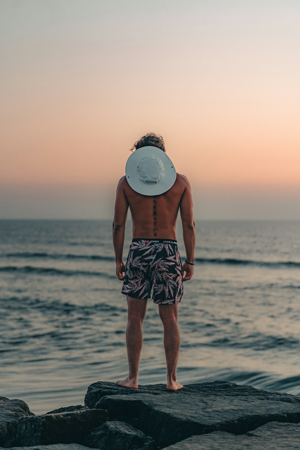 a man standing on a rock with a hat on his head