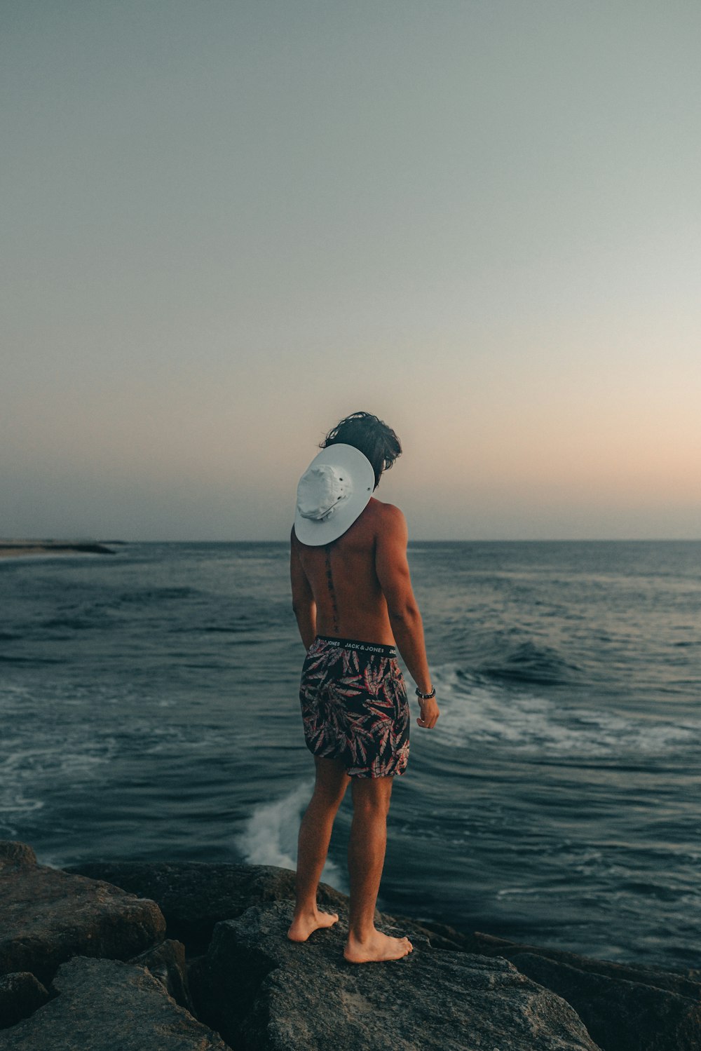 a man standing on top of a rock next to the ocean