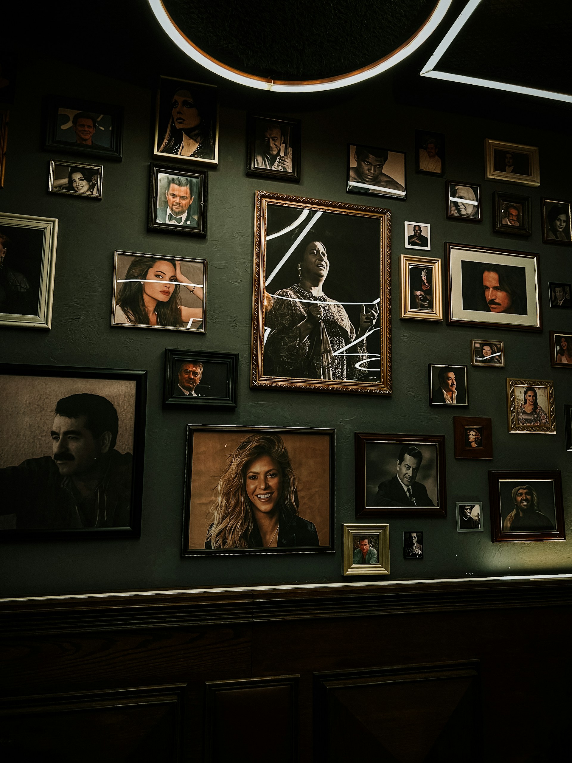 A sleek tasveer digital portrait glowing softly on a living room wall, framed elegantly like a classic painting.