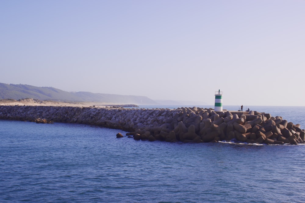 a light house sitting on top of a rock wall next to the ocean