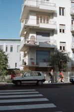 Close-up of hands exchanging keys in front of a new residential building.