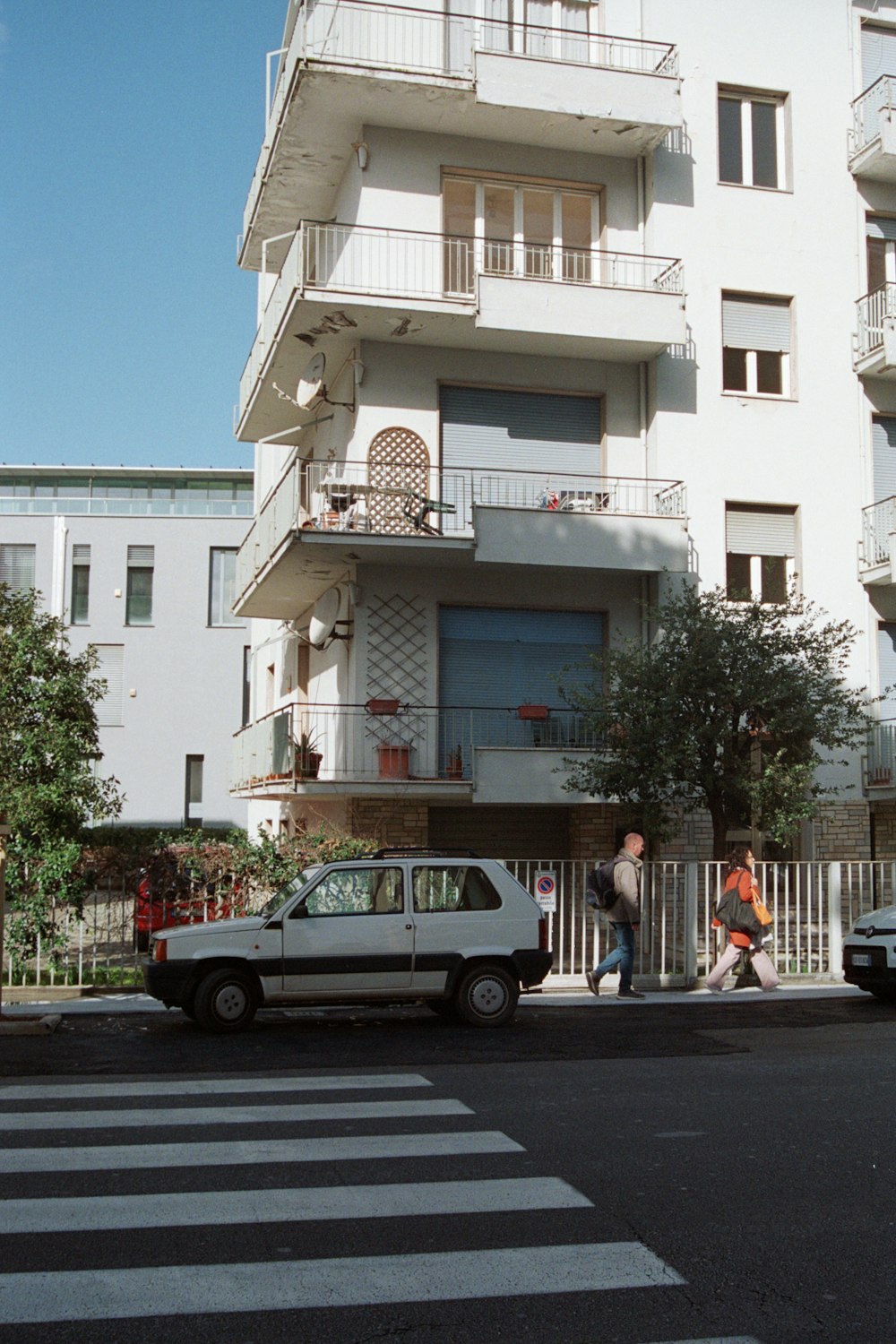 a white car parked in front of a tall building