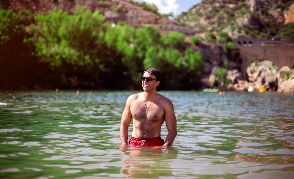 a shirtless man standing in the middle of a body of water