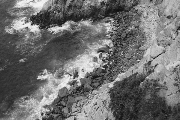 A black and white photo of a rocky coastline — Huatulco, Mexico