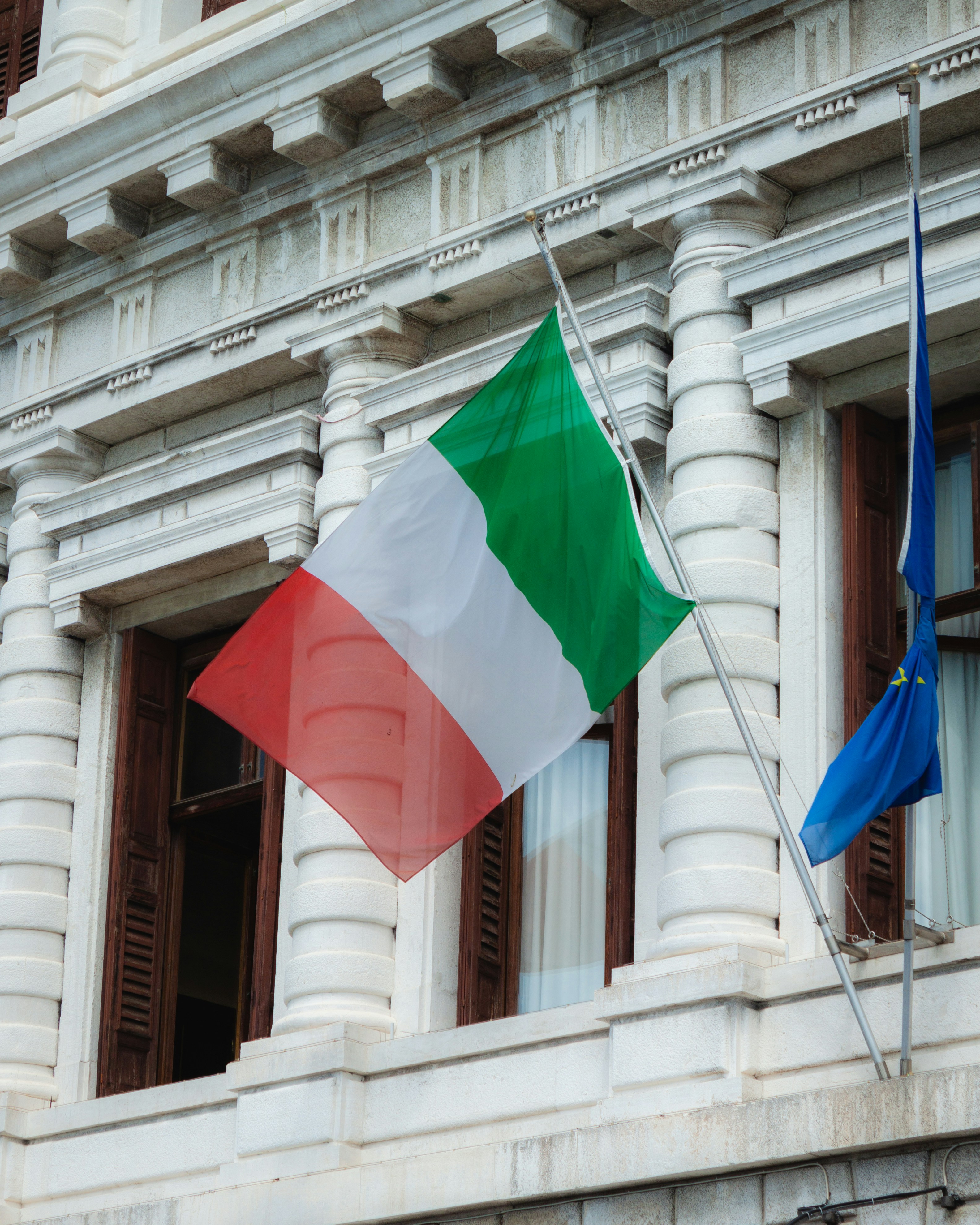 two flags are flying in front of a building